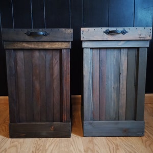 May include: Two wooden trash cans with black metal handles. The trash cans are made of reclaimed wood and have a rustic finish.