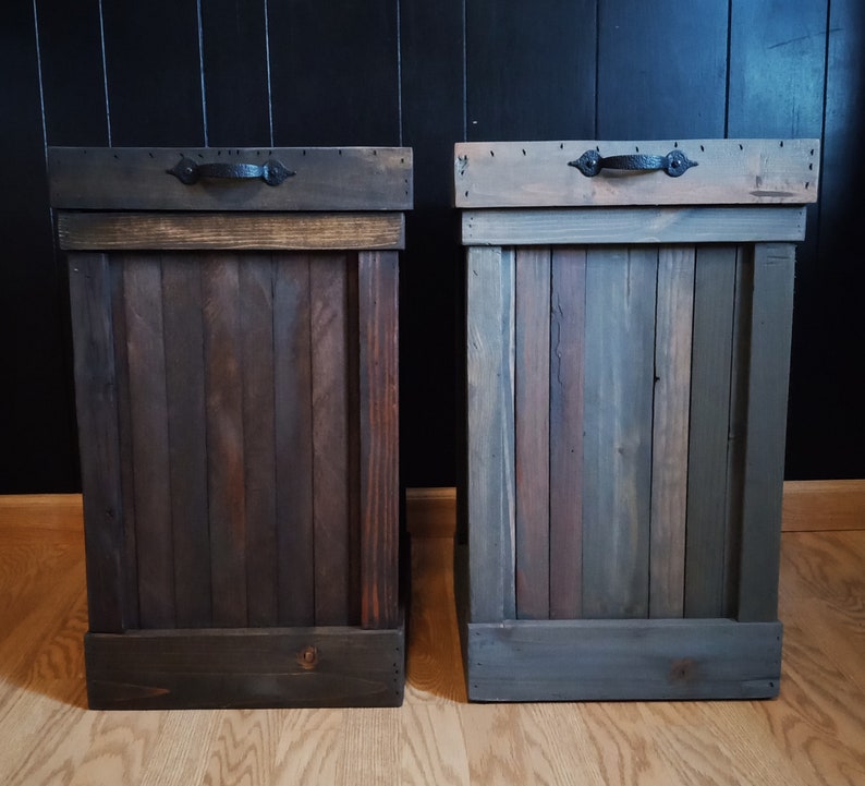 May include: Two wooden trash cans with black metal handles. The trash cans are made of reclaimed wood and have a rustic finish.