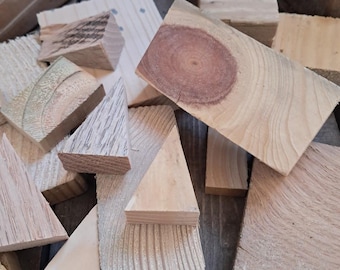 Op de afbeelding: Een stapel van verschillende stukken hout in verschillende maten en vormen, sommige met een natuurlijke houtnerf en andere met een verweerde uitstraling.
