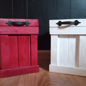 May include: Two wooden storage boxes with black metal handles. One box is painted red and the other is painted white.