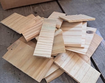 Op de afbeelding: Een stapel natuurlijke houten wiggen, ook wel houten wiggen genoemd, in verschillende maten. De wiggen zijn gemaakt van onbehandeld, lichtbruin hout.
