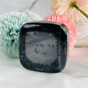 Puede incluir: Una pastilla de jabón negra con las palabras "Shungite Soap" en relieve en la parte delantera.