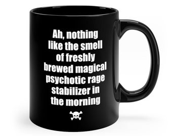 May include: Black coffee mug with white text that reads "Ah, nothing like the smell of freshly brewed magical psychotic rage stabilizer in the morning" and a skull and crossbones symbol.