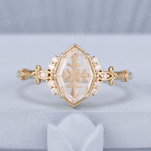 May include: A gold ring with a clear hexagonal stone featuring a snowflake design. The stone is surrounded by smaller diamonds.