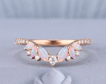 May include: A delicate rose gold wedding band with a curved design. The band is adorned with small white opal and diamond stones.