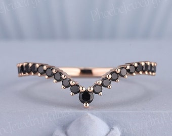 May include: A delicate rose gold ring with a V-shaped band adorned with black gemstones. The ring is a simple and elegant design, perfect for a wedding band or a statement piece.