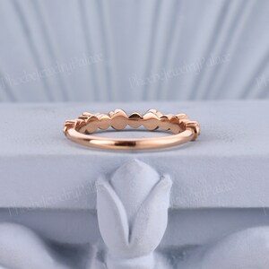 Pode incluir: Um delicado anel de banda de ouro rosa com uma fileira de pequenos diamantes redondos engastados em pav&eacute;.