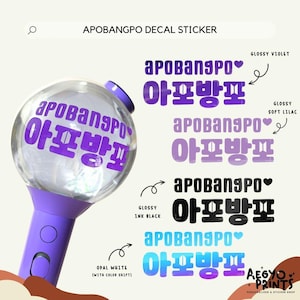Puede incluir: Un palo de luz morado y transparente con el texto "APOBANGPO" en coreano e inglés. La imagen también muestra opciones de calcomanías en violeta brillante, lila suave, negro tinta y blanco ópalo.
