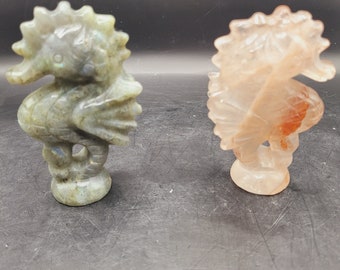 May include: Two seahorse sculptures, one carved from green labradorite and the other from pink quartz.