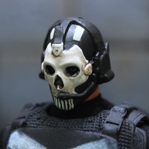 Puede incluir: Una máscara de calavera blanca y negra con un casco negro. La máscara tiene un diseño de calavera blanca con detalles negros. El casco tiene una correa negra y una visera negra.