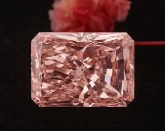 Op de afbeelding: Een grote, rechthoekige, lichtroze diamant met een facetgeslepen vorm. De diamant is geplaatst tegen een zwarte achtergrond.