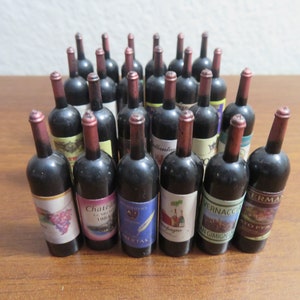 May include: A collection of miniature wine bottles with various label designs. The bottles are dark with red and gold accents, and the labels feature colorful graphics and text. The bottles are arranged closely together.