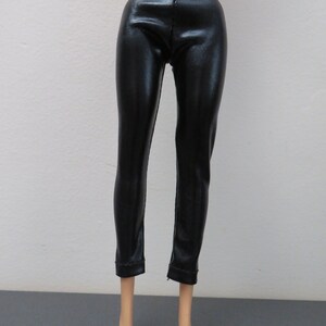May include: Black, shiny, faux leather pants. The pants have a fitted design and a slight sheen. The pants are shown on a doll.