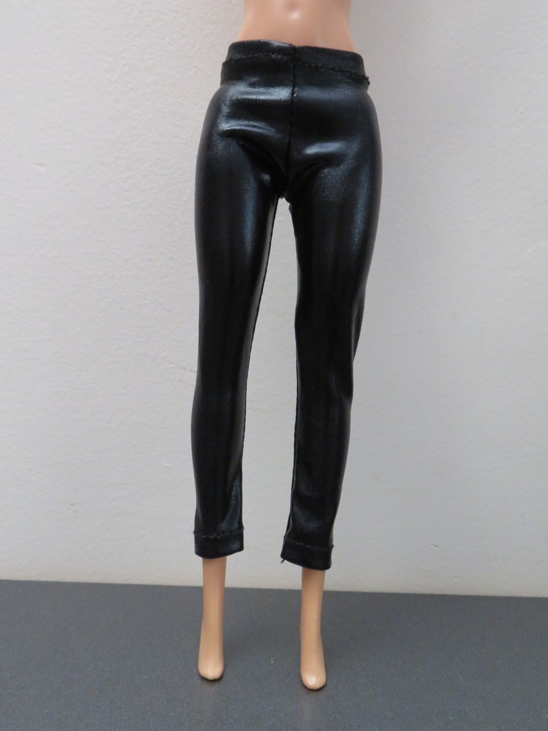 May include: Black, shiny, faux leather pants. The pants have a fitted design and a slight sheen. The pants are shown on a doll.