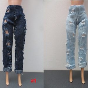 May include: Two pairs of doll jeans: one dark blue, the other light blue. Both have distressed details with ripped sections. The dark blue pair has rolled-up cuffs, and the light blue pair also has rolled cuffs. The jeans are displayed on doll legs.