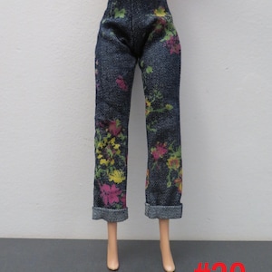 May include: Dark wash denim pants with a floral pattern in pink, yellow, and green. The pants have a straight leg cut and cuffed hems. The number "#20" is printed in red on the bottom right.