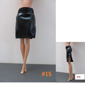 May include: A black, faux leather skirt with a pencil silhouette. The skirt has a slit on the side and a zipper detail. The number "15" is printed in orange in the bottom right corner. The skirt is designed for a doll.