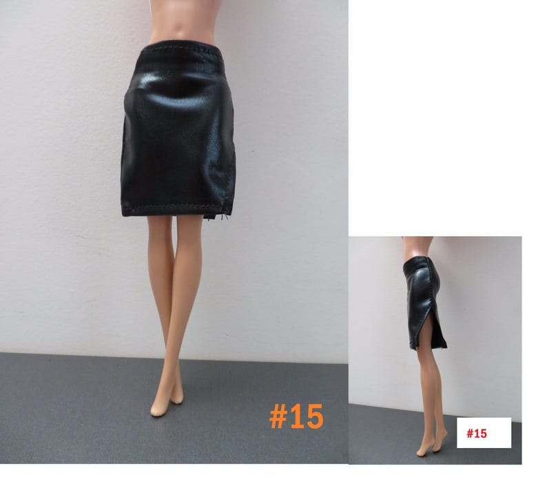 May include: A black, faux leather skirt with a pencil silhouette. The skirt has a slit on the side and a zipper detail. The number "15" is printed in orange in the bottom right corner. The skirt is designed for a doll.