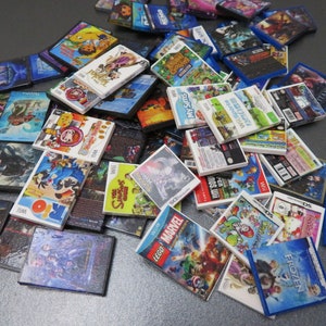 Peut inclure: Une collection de mini-bo&icirc;tiers de jeux vid&eacute;o, avec des titres tels que "Frozen", "LEGO Marvel" et "My Sims". Les bo&icirc;tiers pr&eacute;sentent des illustrations color&eacute;es et des titres de jeux, certains &eacute;tant &eacute;tiquet&eacute;s "Wii" et "DS".