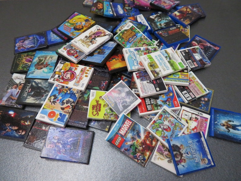 Peut inclure: Une collection de mini-bo&icirc;tiers de jeux vid&eacute;o, avec des titres tels que "Frozen", "LEGO Marvel" et "My Sims". Les bo&icirc;tiers pr&eacute;sentent des illustrations color&eacute;es et des titres de jeux, certains &eacute;tant &eacute;tiquet&eacute;s "Wii" et "DS".