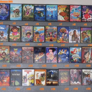 Peut inclure: Une collection de mini-DVD, &eacute;tiquet&eacute;s 1/6 Scale Dollhouse DVD. Les titres incluent "Frozen", "Tangled", "Nemo", "Dory", "Barbie", "Up", "Dora", "Toy Story", "Mulan", "Shrek", et plus encore. Les bo&icirc;tiers sont dispos&eacute;s en rang&eacute;es.