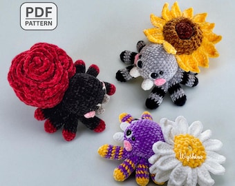 May include: Three handmade crochet plush toys: a black spider with a red rose, a gray spider with a sunflower, and a purple spider with a daisy. The toys have pink cheeks and are on a light gray background. The top left corner has a "PDF PATTERN" label.