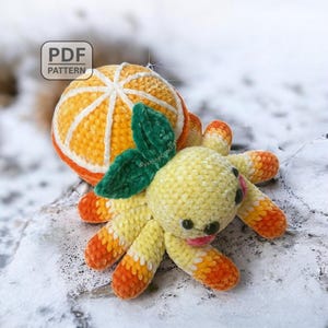 May include: A handmade crochet octopus toy with an orange slice design. The octopus is yellow with orange and white accents, green leaves, and black eyes. The orange slice is orange and white. The text "PDF PATTERN" is in the upper left corner.