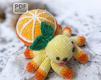 May include: A handmade crochet octopus toy with an orange slice design. The octopus is yellow with orange and white accents, green leaves, and black eyes. The orange slice is orange and white. The text "PDF PATTERN" is in the upper left corner.