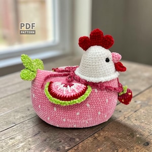May include: A handmade crochet chicken in pink with white spots, a white head, and a red comb. The chicken has a strawberry design on its side and a small strawberry attached. The text "PDF PATTERN" is visible.