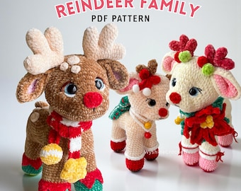 May include: Three crocheted reindeer toys with plush texture. The largest is brown with cream antlers, a red nose, and a red and white scarf. The smaller two are cream-colored with festive red and green accents, including poinsettia details. Text reads: REINDEER FAMILY PDF PATTERN.