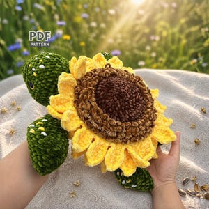 Pode incluir: Uma tartaruga de pelúcia verde com um grande girassol amarelo e castanho preso à sua carapaça. O girassol tem pétalas amarelas e um centro castanho. O texto "PDF PATTERN" está no canto superior esquerdo. Feito à mão.