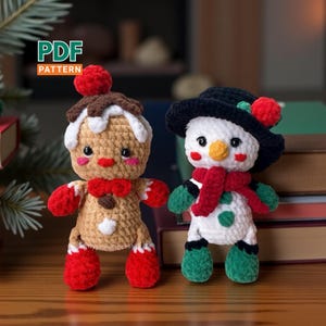 Pode incluir: Dois enfeites de Natal de crochê: um homem de gengibre e um boneco de neve. O homem de gengibre tem uma gravata borboleta vermelha, luvas e pés vermelhos e uma cereja no topo. O boneco de neve usa um chapéu preto, um cachecol vermelho e luvas e botas verdes. As palavras "PDF PATTERN" estão no canto superior esquerdo.