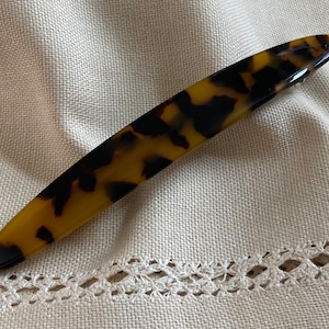 May include: A long, brown and black tortoiseshell hair clip.