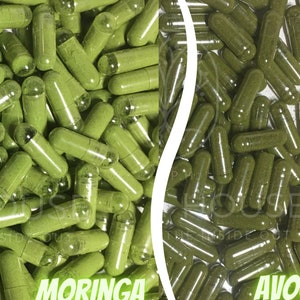 Puede incluir: Imagen de cápsulas verdes, dividida en dos secciones. Un lado está etiquetado como "Moringa" y el otro como "Aguacate". Las cápsulas están llenas de un polvo verde. Las cápsulas tienen forma cilíndrica transparente.