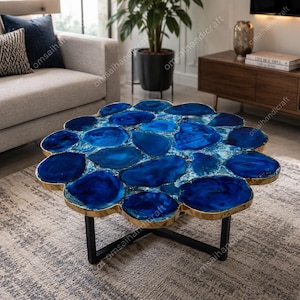 May include: A distinctive coffee table with a floral design. The tabletop is made of polished blue agate stones set in a gold-coloured metal frame. The table is supported by black metal legs, adding a modern touch to the living room.