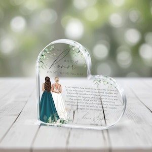 May include: A heart-shaped glass keepsake with a floral design and a message to a maid of honor. The message reads "To my Maid of Honor on my Wedding Day." The message continues with a heartfelt message about the importance of friendship and support. The keepsake also includes a signature and date.