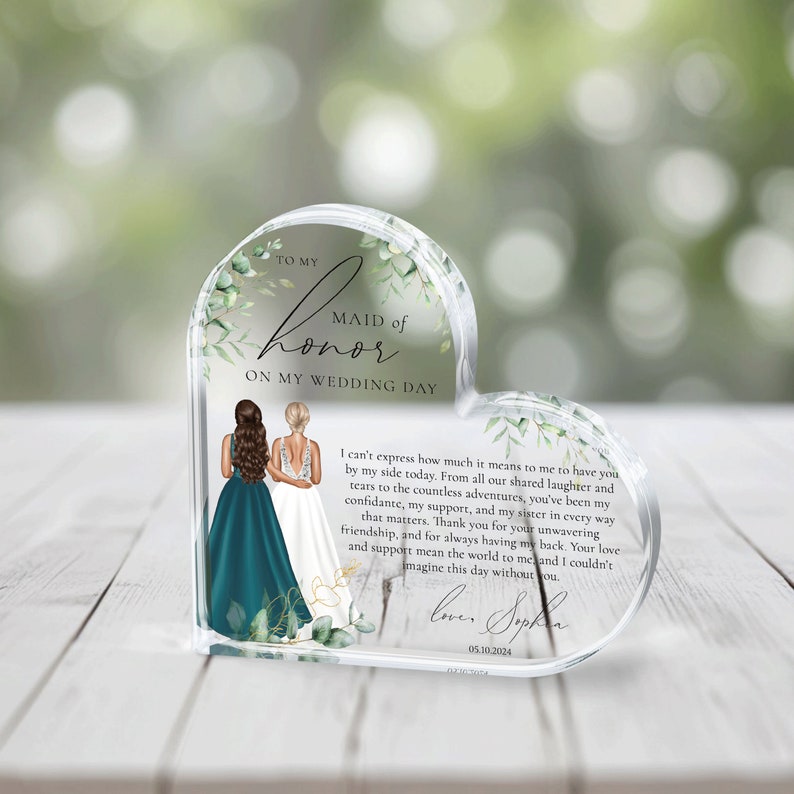 May include: A heart-shaped glass keepsake with a floral design and a message to a maid of honor. The message reads "To my Maid of Honor on my Wedding Day." The message continues with a heartfelt message about the importance of friendship and support. The keepsake also includes a signature and date.