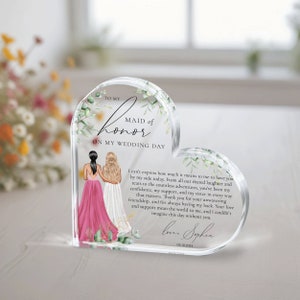 May include: A heart-shaped acrylic keepsake with a floral design and a message to a maid of honor. The text reads "To my Maid of Honor on my Wedding Day." The message continues with a heartfelt sentiment about the importance of the friendship and support of the maid of honor. The text is signed "Love, Sophia" and dated "05.10.2024".