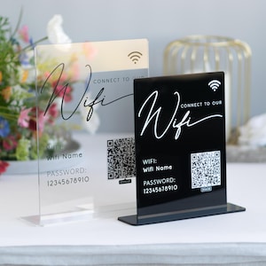 Könnte beinhalten: Zwei Acrylschilder mit schwarzem Text und einem QR-Code. Der Text auf den Schildern lautet "Connect to our Wifi" und "Wifi Name" mit dem Passwort darunter.