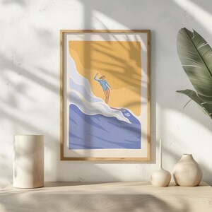 Peut inclure: Une illustration encadrée d'une femme en maillot de bain bleu surfant sur une vague. L'arrière-plan est de couleur jaune et bleue avec un soleil qui brille.