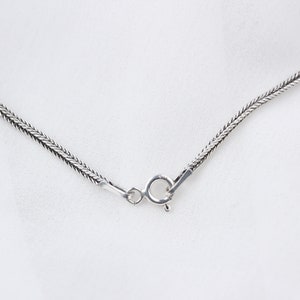 Op de afbeelding: Een zilveren ketting met een karabijn sluiting.