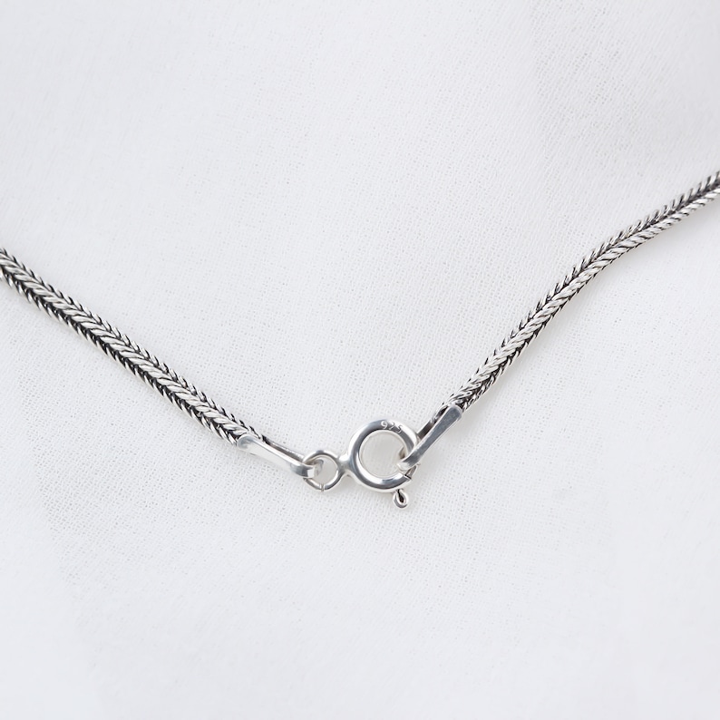 Op de afbeelding: Een zilveren ketting met een karabijn sluiting.