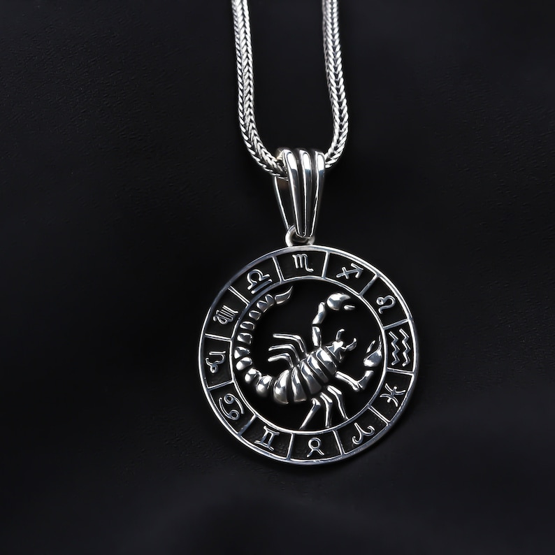 Op de afbeelding: Zilveren ketting met hanger met een cirkelvormig zodiac symbool met een schorpioen en de astrologische tekens van de dierenriem. De ketting is een zilveren boxketting.