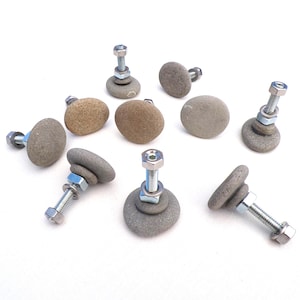 May include: A selection of handcrafted cabinet knobs made from smooth, grey and brown river stones. Each knob is attached to a metal bolt with a nut and washer. The knobs vary in size and shape, offering a natural, rustic aesthetic.