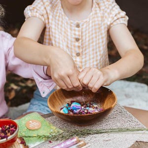 Child playing with fairy potion kit mixing colourful ingredients in sensory play tray