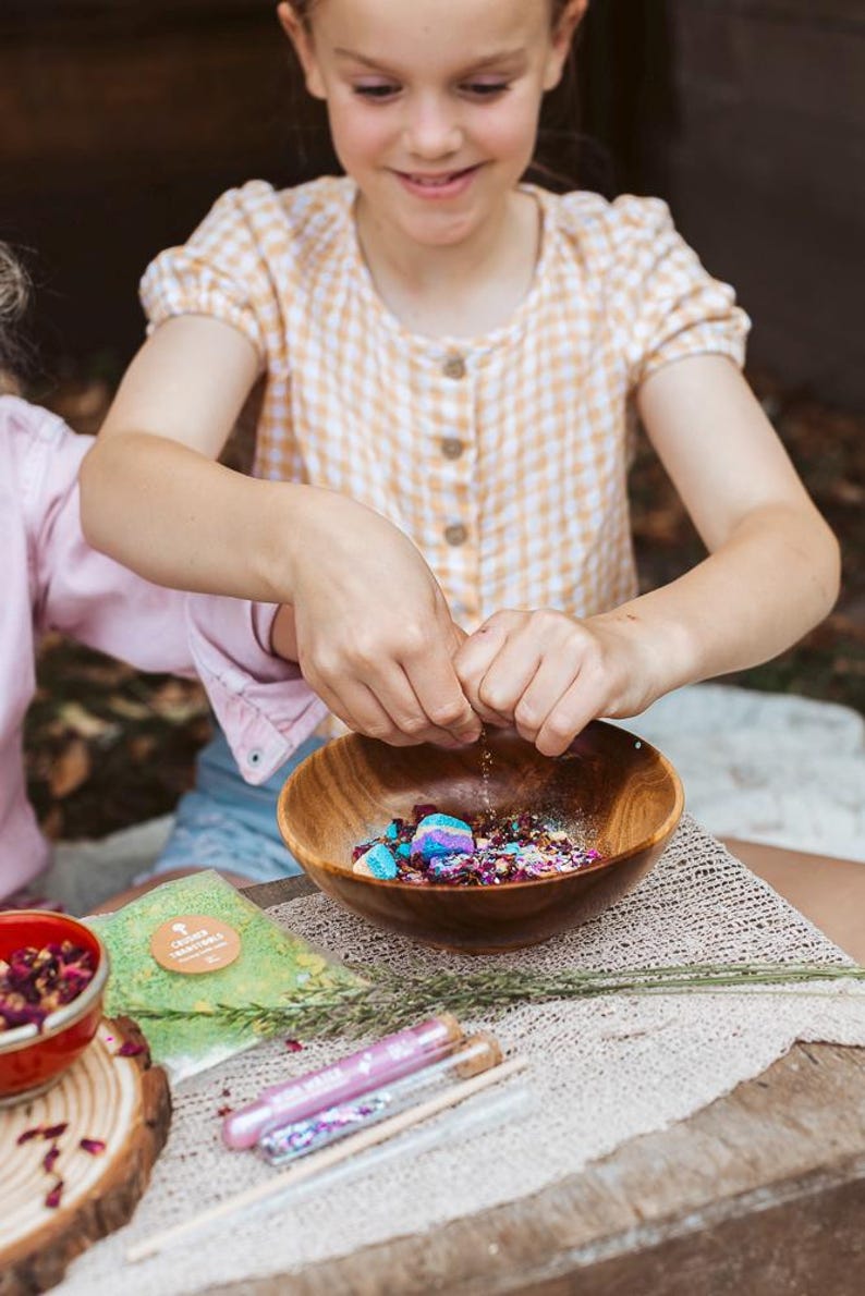 Child playing with fairy potion kit mixing colourful ingredients in sensory play tray