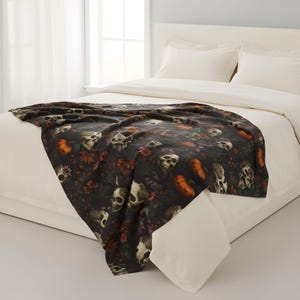 Skull and pumpkin velveteen blanket layered over a bed in a bright bedroom.