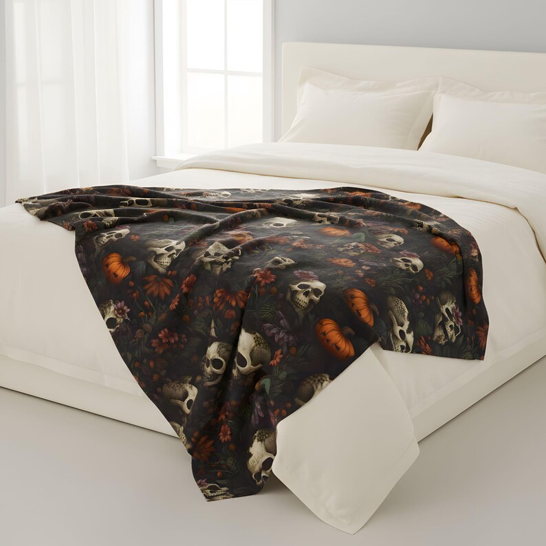 Skull and pumpkin velveteen blanket layered over a bed in a bright bedroom.