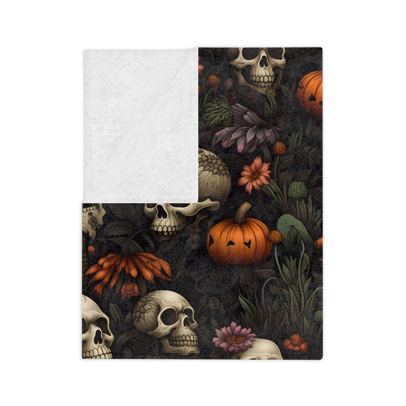 Close-up of Dead Harvest blanket featuring skulls, pumpkins, and moody botanical details with white backside.