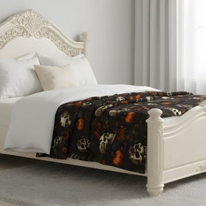 Dead Harvest skull blanket styled on a bed with soft Gothic autumn color and moody pattern.